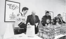  ??  ?? Nashville Predators’ Roman Josi, left, and Lytle Thomas, president of Nashville Inner City Ministry, along with Winnipeg Jets defenseman Dustin Byfuglien and Vancouver Canucks’ Daniel Sedin, fill bags of food Friday at the NHL AllStar Legacy Family...