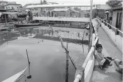  ??  ?? STAYING PUT — While most of their neighbors have opted to stay in hotels to avoid nauseous fumes emanating from the oil spill that hit the river, some residents of three coastal villages in Iloilo City have opted to precarious­ly stay home like these children playing by the riverbank. (Tara Yap)