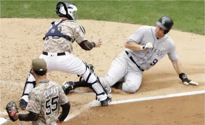  ??  ?? SAN DIEGO: Colorado Rockies’ DJ LeMahieu, right, slides in late to home and is tagged out by San Diego Padres catcher Austin Hedges during the fourth inning of a baseball game Sunday, in San Diego. — AP