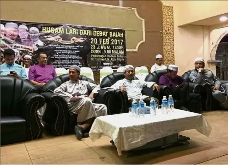  ??  ?? Unwanted visitor: Husam (in purple shirt) sitting behind Nasuruddin (wearing turban with beard) after he gatecrashe­d the ‘ceramah’ at the Sultan Muhammad IV Stadium.