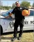  ?? Photo submitted ?? Gentry Police Officer Clay Stewart was one of the customers who bought a pumpkin from the Bonds’ pumpkin stand at The Chicken Coop on Main Street in Gentry.