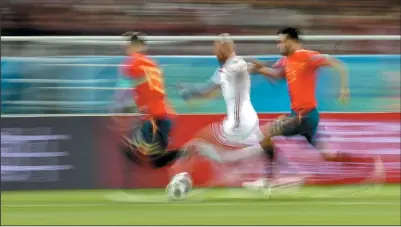  ?? AP PHOTO/PETR DAVID JOSEK ?? In this image shot with a slow shutter speed, Morocco's Noureddine Amrabat, centre, chases the ball between Spain's Sergio Ramos, left, and Sergio Busquets during the group B match between Spain and Morocco at the World Cup at the Kaliningra­d Stadium...