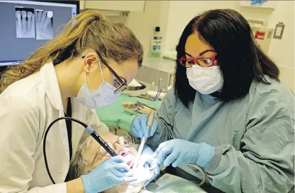  ?? LARRY WONG ?? Patient Wilma Amirault receives treatment Wednesday from Dr. Fern Leavens, left, and assistant Lalaine Jovellanos at the Glenrose Rehabilita­tion Hospital, where Health Minister Sarah Hoffman announced a new dental fee guide that suggests a drop of 8.5...