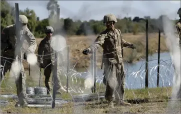  ?? ERIC GAY — THE ASSOCIATED PRESS ?? Members of the U.S. military install multiple tiers of concertina wire along the banks of the Rio Grande near the JuarezLinc­oln Bridge at the U.S.-Mexico border in Laredo, Texas.