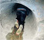  ??  ?? A protester crawls into a sewer tunnel to check its width in a bid to escape from the Hong Kong Polytechni­c University campus. Above, another emerges from a sewer after failing to find a way out