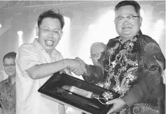  ??  ?? Sempurai (right) presents a memento to Dr Sim.