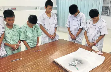  ?? Picture: Chiang Rai Prachanukr­oh Hospital and ministry of public health/handout via REUTERS ?? PAYING TRIBUTE: Members of the ‘Wild Boars’ soccer team rescued from a flooded cave bow their heads at the Chiang Rai Prachanukr­oh Hospital in Chiang Rai, Thailand, after writing messages of condolence on a drawing of Saman Kunan, a former Thai navy...