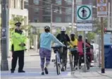  ?? BERNARD WEIL/TORONTO STAR ?? Officer Ghazarian makes sure morning cyclists dismount at a narrow section of the Queen’s Quay cycle path at Dan Leckie Way.