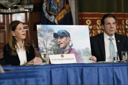  ?? AP PHOTO/HANS PENNINK, FILE ?? Linda Beigel Schulman, left, holds a photograph of her son Scott Beigel, who was killed during the Valentine’s Day massacre at Marjory Stoneman Douglas High School, while speaking with New York Gov. Andrew Cuomo and gun safety advocates during a news conference Jan. 29 at the state Capitol in Albany, N.Y. Since the shooting, states have seen a surge of interest in laws intended to make it easier to disarm people who show signs of being violent or suicidal.