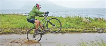  ??  ?? A cyclist makes the most of the rainy downpours and flooded dirt track.