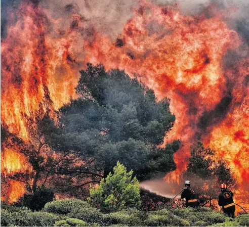  ?? PHOTOS: ANGELOS TZORTZINIS / AFP / GETTY IMAGES ?? Firefighte­rs try to extinguish a wildfire at Kineta, near Athens, Tuesday. Raging wildfires killed 74 people including small children in Greece, devouring homes and forests as terrified residents fled to the sea to escape the flames.