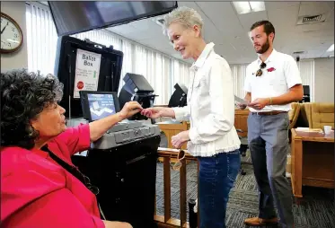  ?? NWA Democrat-Gazette/DAVID GOTTSCHALK ?? Lana Orman (center) receives a sticker Monday from Martha Hill, Washington County election official, after casting her ballot on the last day of early voting at the Washington County Courthouse in Fayettevil­le. Voting in the Arkansas primaries is today.