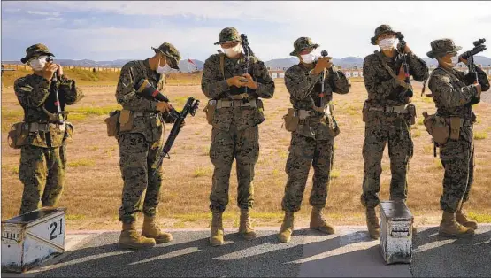  ??  ?? Before moving back to the next rifle range distance while training at Camp Pendleton, recruits from Alpha Company wait to have their weapons safety inspected. Recruits are e issued M-16s and keep them with them throughout training.