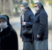  ?? GETTY IMAGES ?? Nuns in Bergamo, Italy, wear masks while standing inside the closed Monumental Cemetery on Friday.