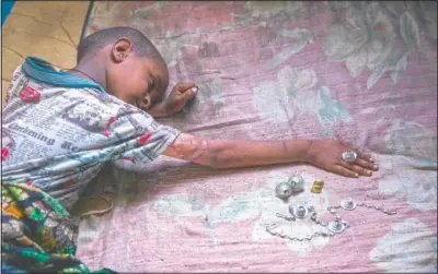  ??  ?? Tigrayan 5-year-old refugee Micheale Gebremaria­m plays with jewelry belonging to his deceased mother, Letay, in the family’s shelter in Hamdayet, Sudan. (AP/Nariman El-Mofty)