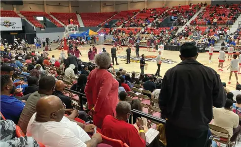  ?? (Pine Bluff Commercial/Byron Tate) ?? Fans stand and stretch as players warm up Monday at the King Cotton tournament at the Pine Bluff Convention Center.