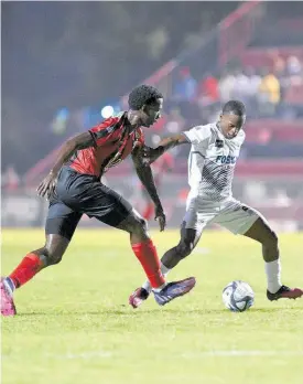  ?? GLADSTONE TAYLOR ?? Cavalier’s Dwayne Atkinson (right) tries to get by Arnett Gardens’ Joel Cunningham during their Jamaica Premiere League recent football match at the Anthony Spaulding Sports Complex. The match drew 2-2.