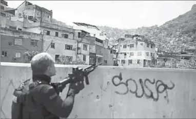  ??  ?? A police officer takes a position during an operation in the Rocinha favela in Rio de Janeiro, Brazil, on Friday.