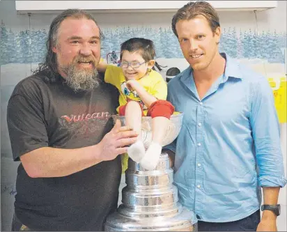  ?? BRIAN MCINNIS/THE GUARDIAN ?? Five-year-old Alcide Costard is just the perfect fit for the Stanley Cup when Brad Richards, right, brought the trophy to the pediatrics ward at the QEH Tuesday. The hockey star, who won the Cup with the Chicago Blackhawks this spring, brought the NHL...