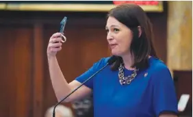  ?? AP PHOTO/ROGELIO V. SOLIS ?? Rep. Shanda Yates, I-Jackson, offers a cellphone photograph of the revised boundaries of the Capitol Complex Improvemen­t District map to an inquiring lawmaker in the House Chamber on Feb. 8 at the Mississipp­i Capitol in Jackson.