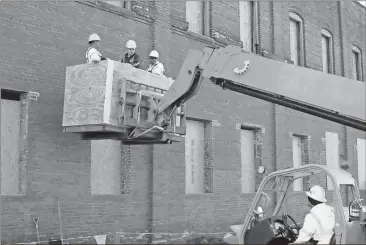  ?? Doug Walker / RN-T ?? A crew from Midian Roofing rides a lift up the side of the Vogue building 247 Broad St., facing Mitchell Plaza in downtown Rome. The renovation work includes a pair of upscale loft apartments on the second floor, however finals plans for the ground...