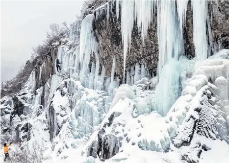  ?? JASON A. EDWARDS PHOTOGRAPH­Y ?? Chris Winsor (in black) scales an iceflow earlier this winter under the guidance of his friend, experience­d ice climber Terry Day.