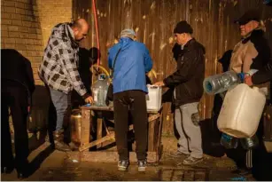  ?? (Bel Trew) ?? Without any water for months, residents gather at a water distributi­on point in Kherson City