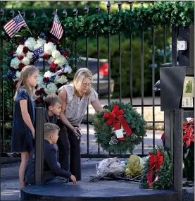  ?? AP/DAVID J. PHILLIP ?? Tiffany Utterson (right) and her children (from left) Ella, 11; Ian, 10; and Owen, 8, place a wreath Sunday outside the gated-community entrance to the home of the late George H.W. Bush in Houston. The casket of the former president, who died Friday, will arrive at the U.S. Capitol in Washington tonight, and his funeral is scheduled for Wednesday morning.