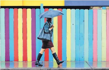  ?? JIM THOMPSON/JOURNAL ?? Lorilynn Violanta walks near Second and Silver as rain pelted Albuquerqu­e on Tuesday. Up to a quarter of an inch of rain fell on the city — the first measurable rainfall since April 1.