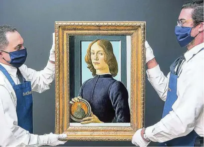  ?? EFE ?? Dos trabajador­es de la casa de subastas sostienen entre sus manos la obra «Joven sujetando un medallón», pintada por Botticelli