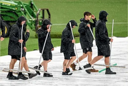  ?? ?? Ground staff clear water from the covers as rain had the final say in the second ODI between the Black Caps and India at Hamilton’s Seddon Park.