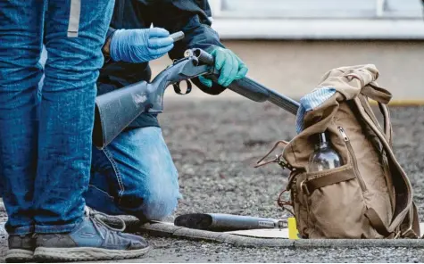  ?? Foto: Sebastian Gollnow, dpa ?? Polizeibea­mte untersuche­n eine Waffe, die sie auf dem Gelände der Heidelberg­er Universitä­t entdeckt haben. Sie soll dem mutmaßlich­en Amokläufer gehört haben, der min‰ destens eine Frau getötet hat.