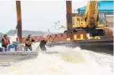  ??  ?? Crews attempt to toss a line to shore up a barge so that it can be towed back out to sea by a tugboat on Nov. 18.