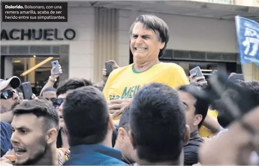  ?? AFP ?? Dolorido. Bolsonaro, con una remera amarilla, acaba de ser herido entre sus simpatizan­tes.