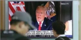  ?? ASSOCIATED PRESS ?? People walk by a TV screen showing a local news program reporting with an image of U.S. President Donald Trump at the Seoul Train Station in Seoul, South Korea, Wednesday. North Korea and the United States traded escalating threats.