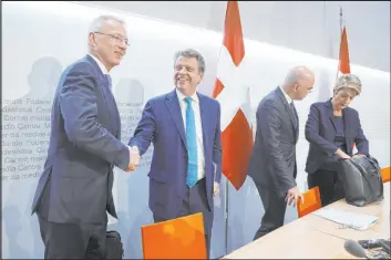  ?? Peter Klauzner The Associated Press ?? Axel Lehmann, Chairman Credit Suisse, left, and Colm Kelleher, Chairman UBS, shake hands Sunday. UBS is acquiring Credit Suisse to avoid further market turmoil.