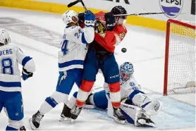  ?? Wilfredo Lee/associated Press ?? Panthers center Anton Lundell and Lightning defenseman Matt Dumba battle for position as a shot bounces off goaltender Andrei Vasilevski­y during the second period on Sunday in Sunrise, Fla.