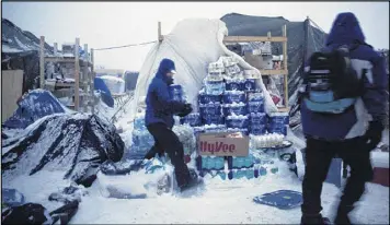  ?? DAVID GOLDMAN / ASSOCIATED PRESS ?? Ray Franks of New York carries water from storage at the Oceti Sakowin protest camp in Cannon Ball, N.D., on Tuesday. Opponents of the Dakota Access oil pipeline say they’ll maintain the camp through the winter.