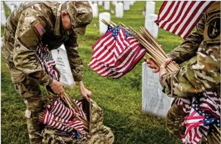  ?? AP ?? Members of the 3rd U.S. Infantry Regiment place flags in front of headstones to honor fallen service members at Arlington National Cemetery on Thursday ahead of Memorial Day. The enormity of the debt we owe our fallen is difficult to fathom as large numbers tend to obscure the individual humanity of sacrifice, the author writes.