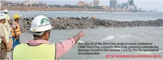  ??  ?? An official of the Port City project’s main contractor CHEC Port City Colombo (Pvt.) Ltd, pointing towards the damage caused to the armour rock by the sea because of the suspension.
PICBYROMES­HDHANUSHKA­SILVA