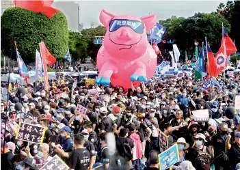  ?? —AP ?? People hold a pig model with “I am a ractopamin­e pig” written on it during a protest in Taipei, on Sunday.