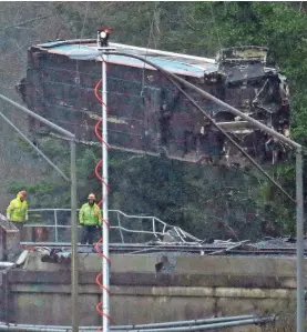  ?? ELAINE THOMPSON/AP ?? A damaged Amtrak train car is lowered from an overpass above Interstate 5 on Tuesday in DuPont, Wash. Federal investigat­ors are trying to determine why the Amtrak train was traveling about 50 mph over the speed limit when it derailed Monday south of...