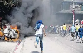  ?? DIEU NALIO CHERY/AP ?? Protesters run after cars were set on fire near the Best Western Premiere hotel during protests over a fuel price increase Saturday.