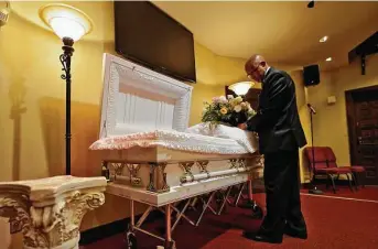  ?? Chris O'Meara / Associated Press ?? Wayne Bright, funeral director at Wilson Funeral Home, arranges flowers on a casket before a service Thursday in Tampa, Fla. Bright has seen grief piled upon grief during the latest surge.