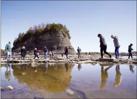  ?? AP file photo ?? People walk to Tower Rock, an attraction normally surrounded by the Mississipp­i River and only accessible by boat, Oct. 19, in Perry County, Mo. Foot traffic to the rock formation has been made possible because of near record low water levels along the river.