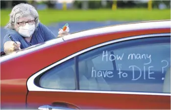  ?? BOB SELF/THE FLORIDA TIMES-UNION ?? Registered nurse Laure Hale writes on her car Tuesday before joining a motorcade to the Duval County school board building in Jacksonvil­le, Florida, where teachers and their supporters protested reopening plans amid the pandemic.