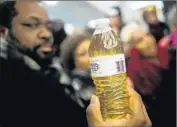  ?? Jake May Associated Press ?? A PROTESTER raises a bottle of Flint tap water at a rally calling for Gov. Rick Snyder’s resignatio­n.