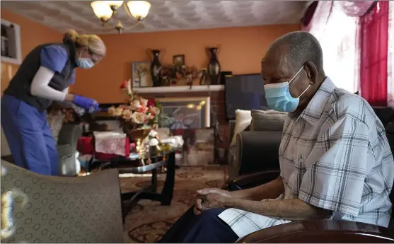  ?? THE ASSOCIATED PRESS ?? Edouard Joseph, 91, clasps his hands as geriatrici­an Megan Young prepares to give him a COVID-19vaccinat­ion at his home in the Mattapan neighborho­od of Boston.