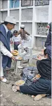  ??  ?? Tradición. Una pareja de otavaleños se alimentan en el cementerio.