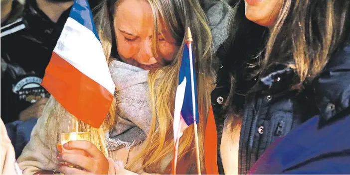  ?? Foto: Reuters, David Gray ?? Smutek i v Austrálii Příslušníc­i francouzsk­é komunity v centru Sydney zapalují svíčky a vzpomínají za zpěvu národní hymny na své krajany z Nice.